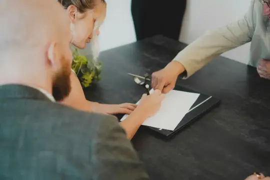 Para z dumą podpisuje dokumenty, finalizując swoją ugoda.