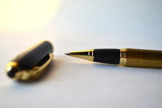 Eleganckie, złote pióro z czarną skuwką leży obok, gotowe do złożenia ważnej kontrasygnaty.